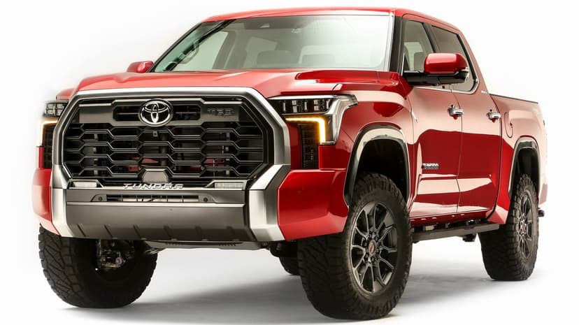Red Toyota Tundra TRD pickup truck with a large black grille and rugged tires against a bright white background.