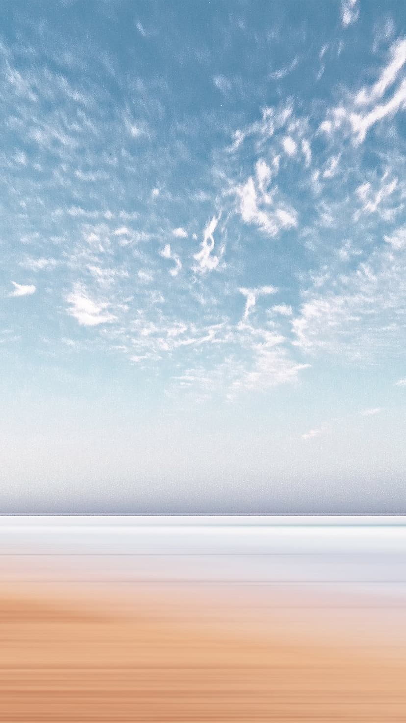 Cerulean sky with wispy clouds transitions into blurred white mist and streaked ochre sand dunes.