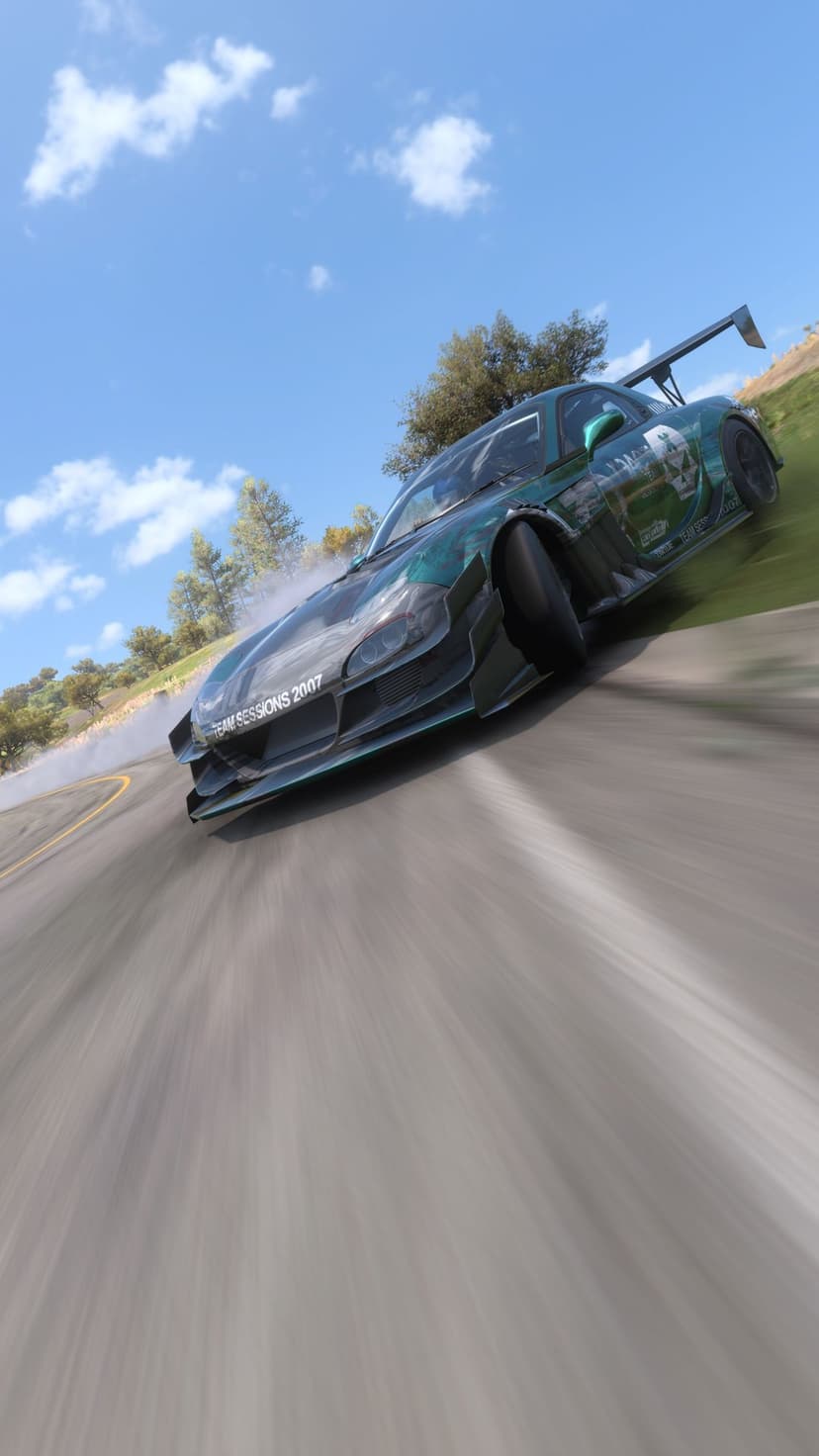 Green sports car drifting around a paved corner with white tire smoke against a sunny hill and cloudy sky background.