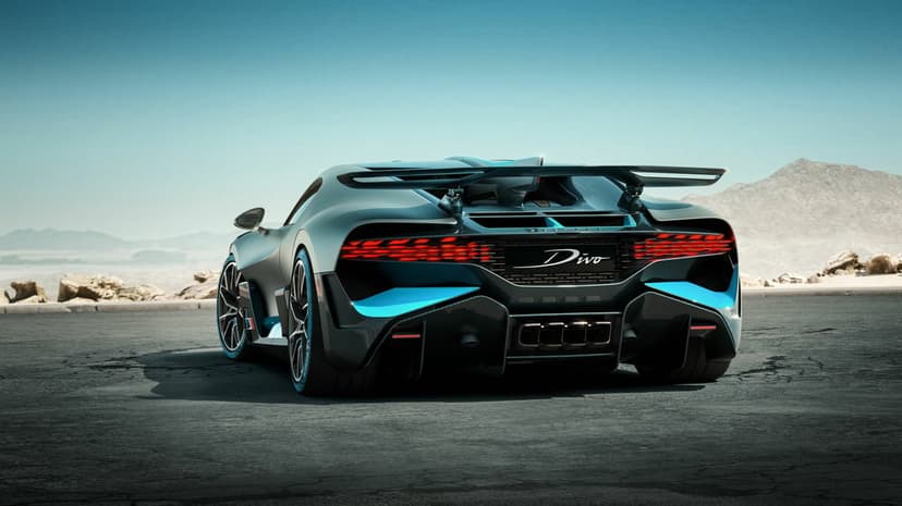 Bugatti Divo rear view with red LED tail lights and blue accents on a desert road under a clear blue sky.