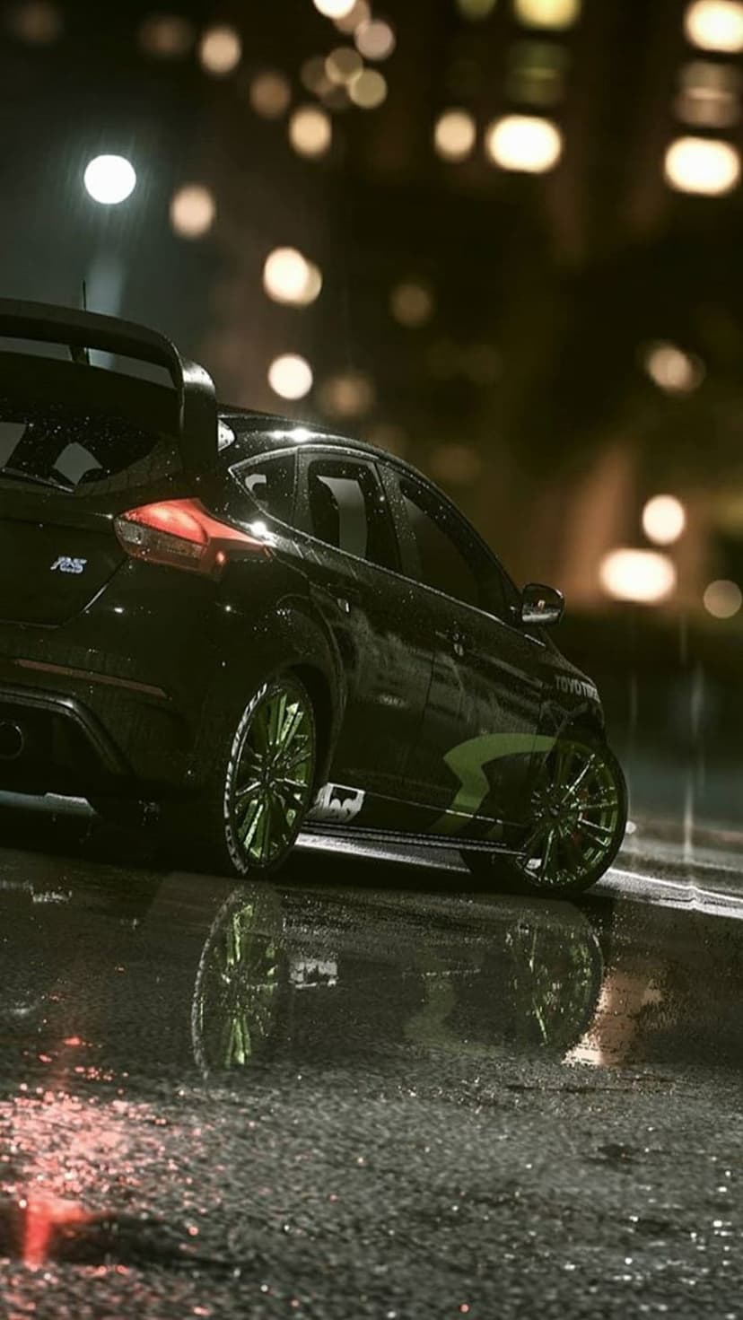 Black Ford Focus RS with bright green wheels parked on a wet asphalt road at night under glowing city bokeh.