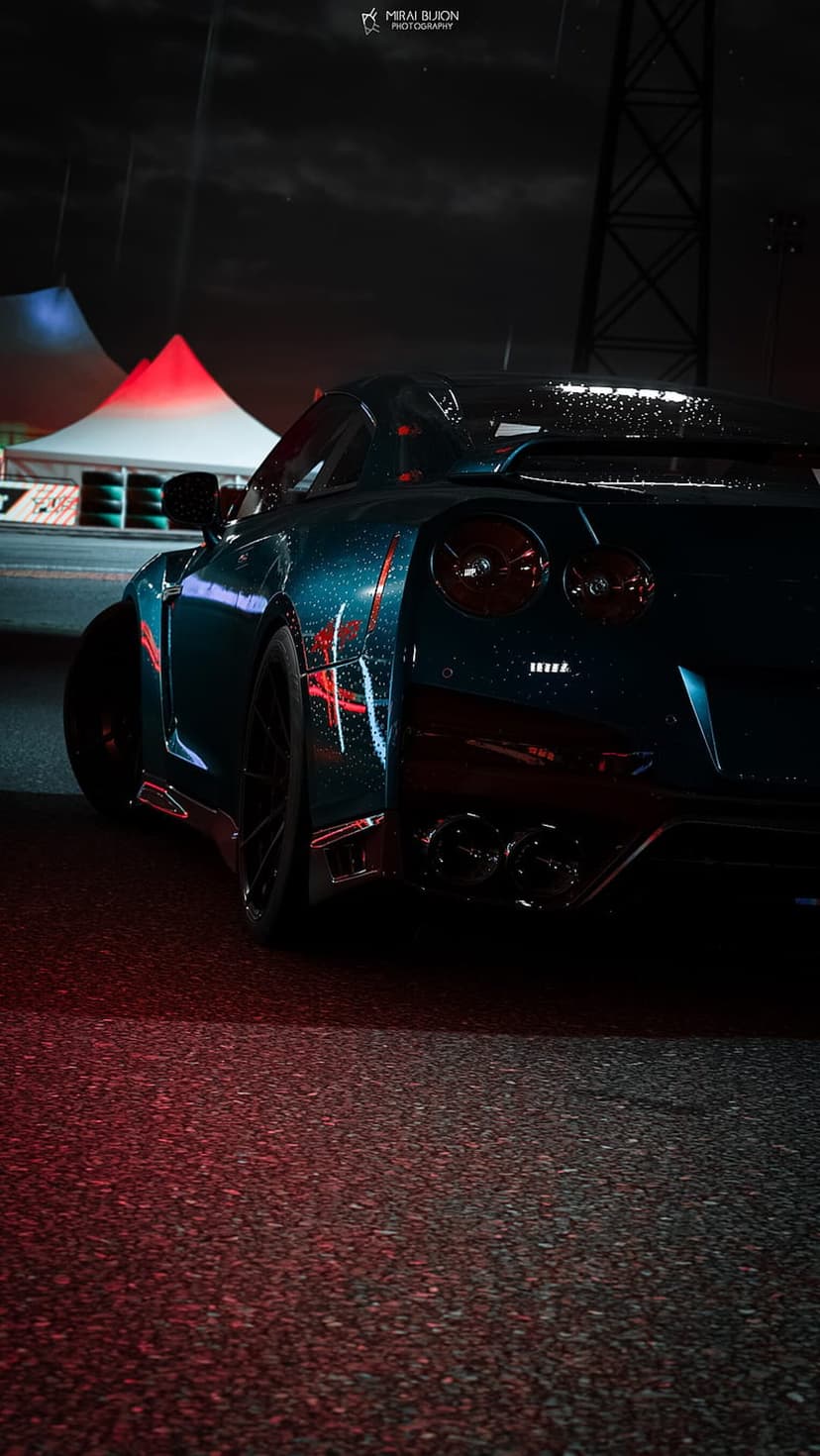 Teal Nissan GT-R reflects glowing red circuit lights on a rainy asphalt track under a dark, moody night sky.