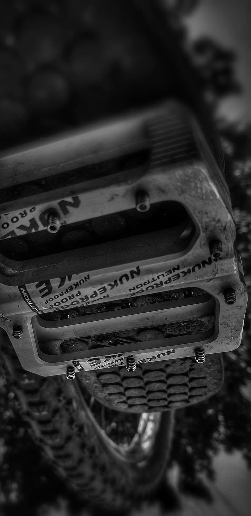 Nukeproof Neutron mountain bike pedals with metal pins shown in a high-contrast black and white macro view.