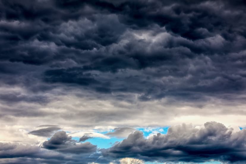 Dark heavy storm clouds with wispy gray textures and patches of blue sky visible in the distance.