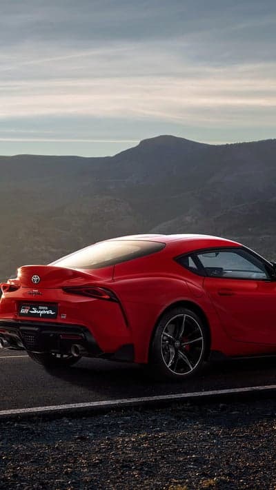 Red Toyota Supra GR rear view on mountain road