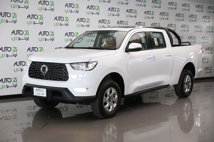 White dual-cab pickup truck with a black honeycomb grille on a reflective showroom floor under bright lights.