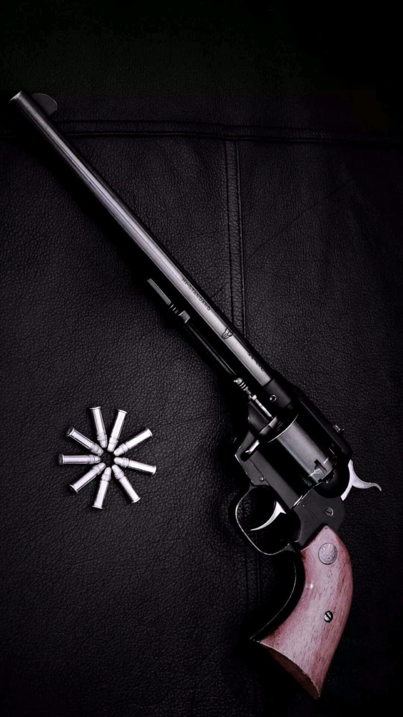 Black revolver with wood grip next to circular ammo on textured leather, serving as a vertical screen backdrop.