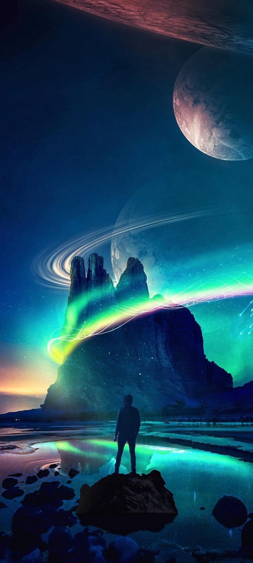 Silhouetted man stands on a rocky cliff watching green auroras and ringed planets over a calm lake at night.