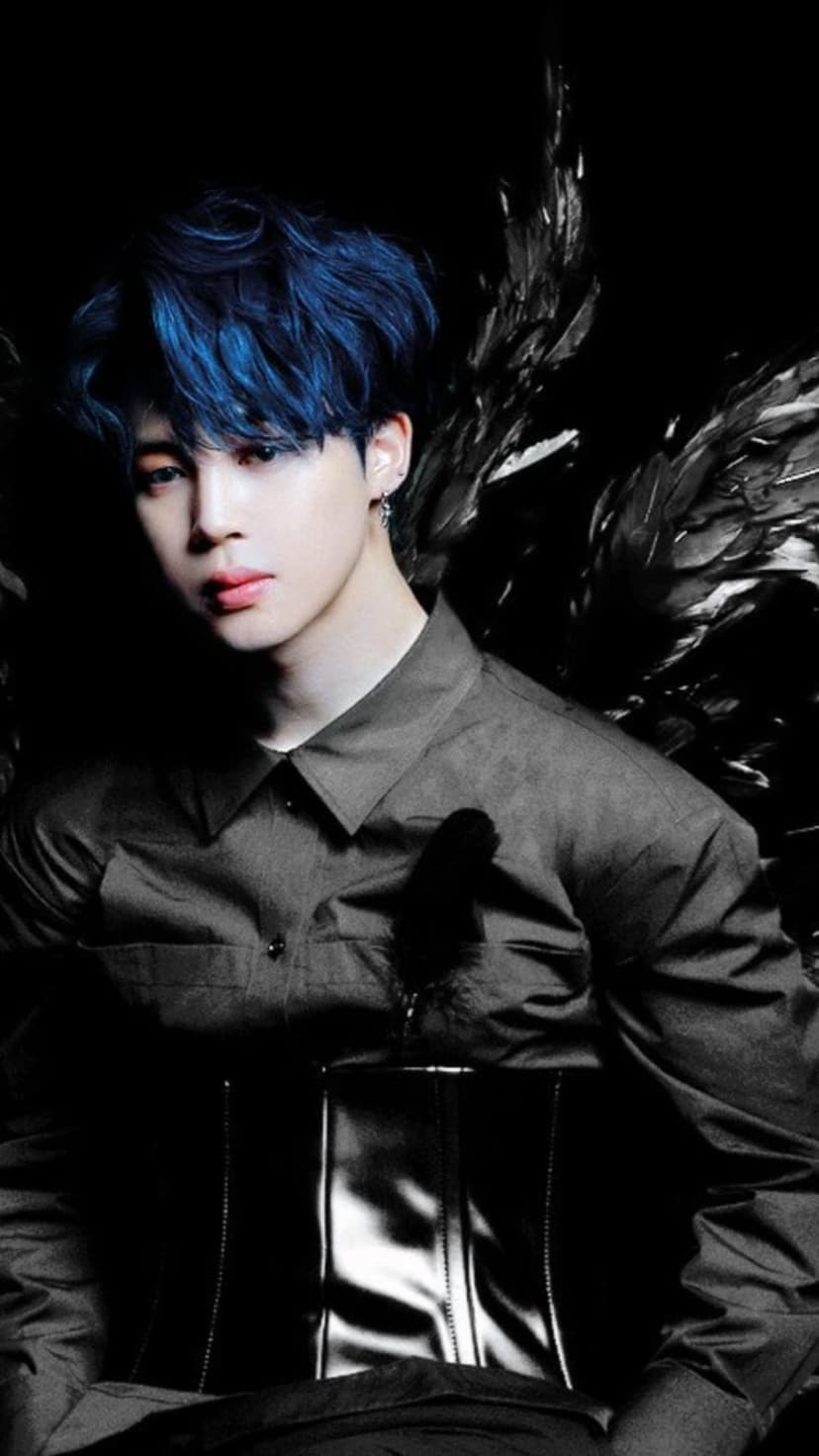 Jimin with blue hair and black feathered wings wearing a dark corset under dramatic high-contrast studio lighting.