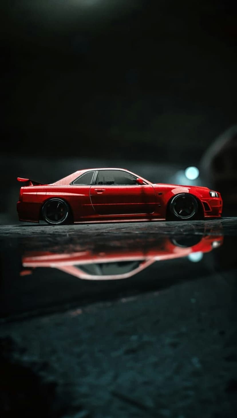 Red Nissan Skyline GT-R R34 sports car side profile reflecting on wet asphalt in a dark, moody environment.