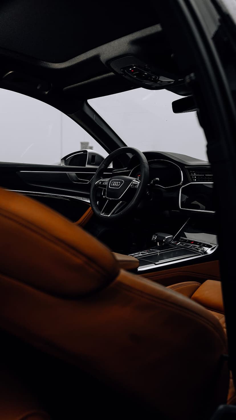 Audi car interior featuring brown leather seats, a leather-wrapped steering wheel, and a glowing digital console.