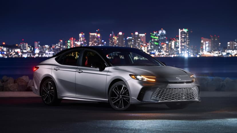 Toyota Camry XSE parked on a wet asphalt street under neon city lights with reflective automotive body panels.