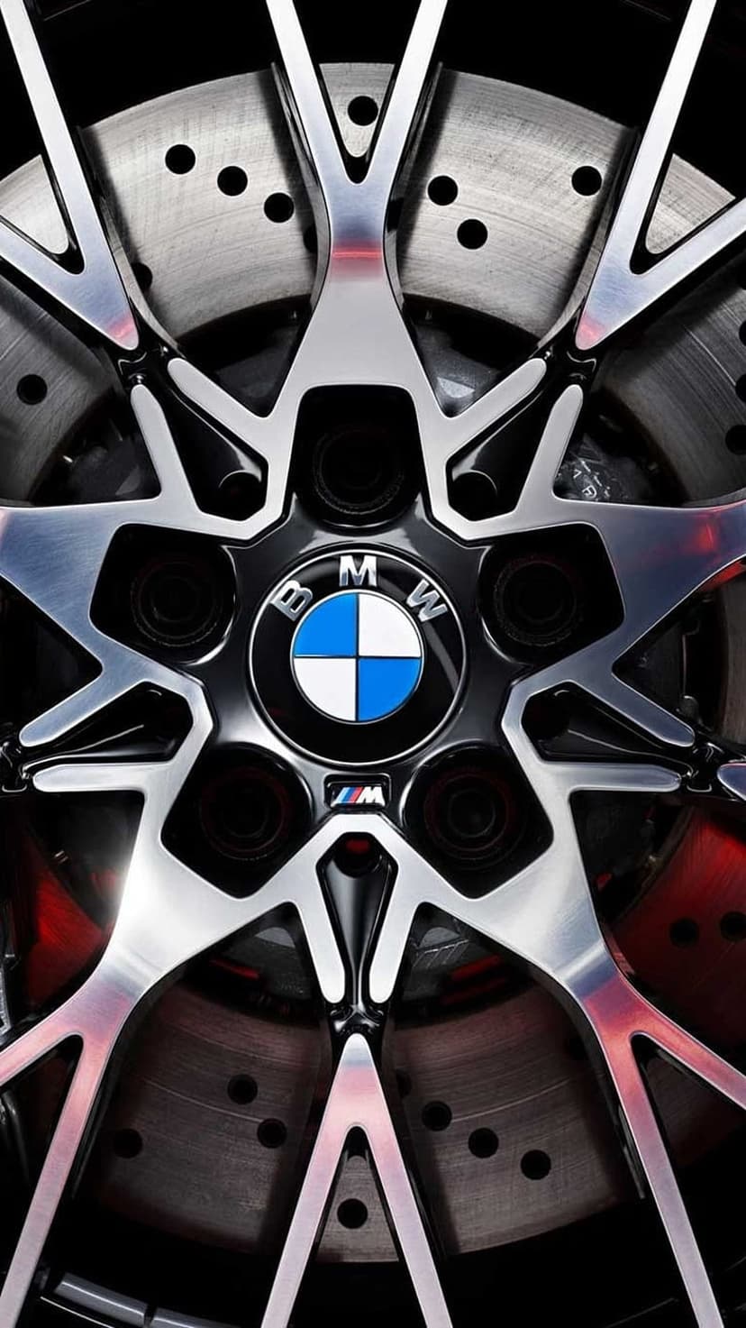BMW M alloy wheel with polished spokes, carbon fiber trim, and a drilled brake rotor on a performance vehicle.