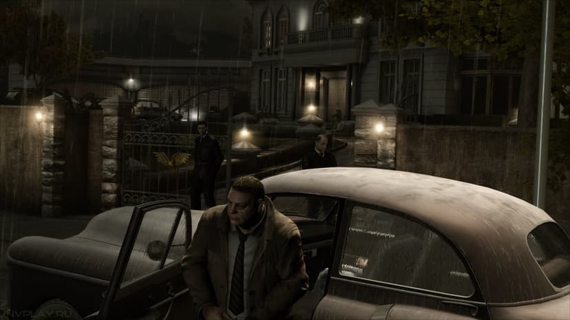 Man in a tan coat exits a classic car during a heavy rainstorm near a guarded mansion gate at night.