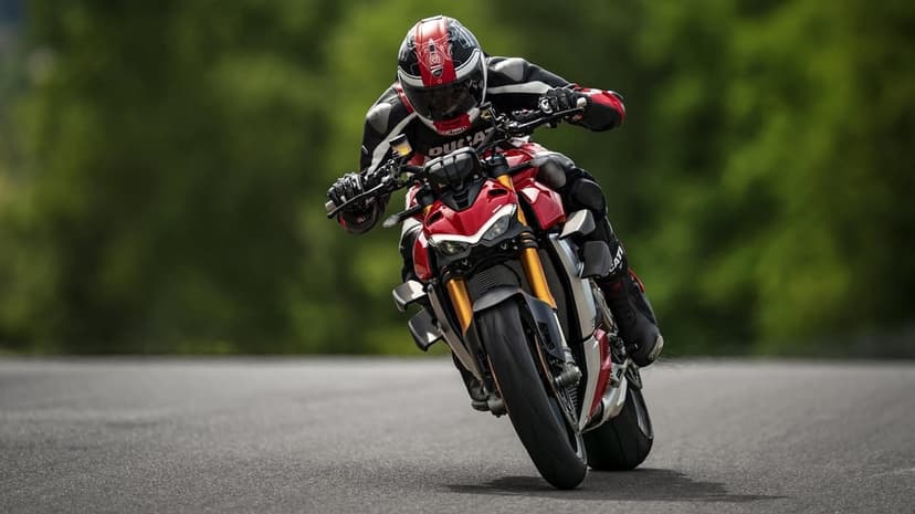 Red Ducati motorcycle leaning into a curve with a rider in full gear on a blurred track background.