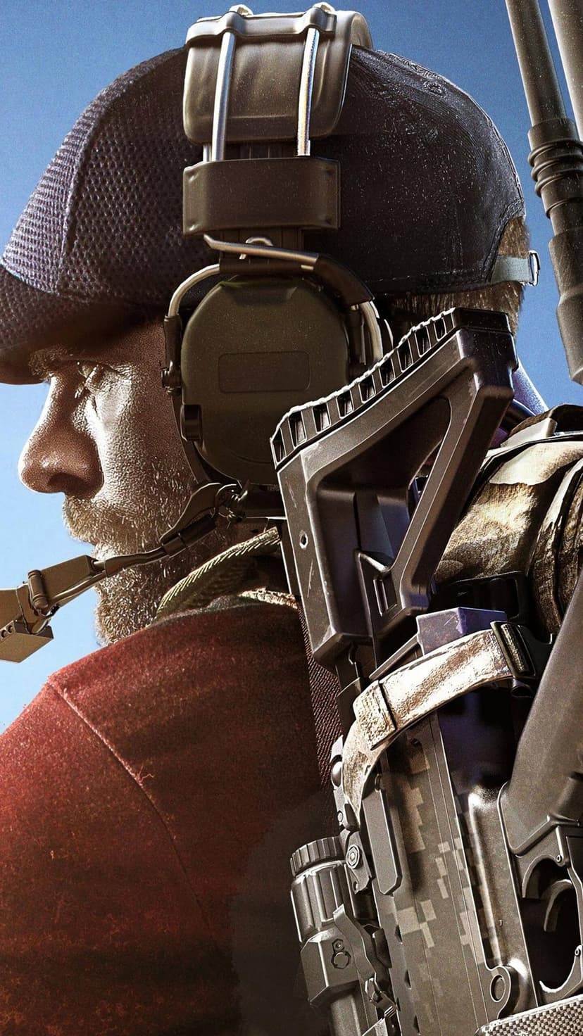 Close-up side profile of a bearded soldier wearing headphones and a cap with a tactical rifle against blue sky.