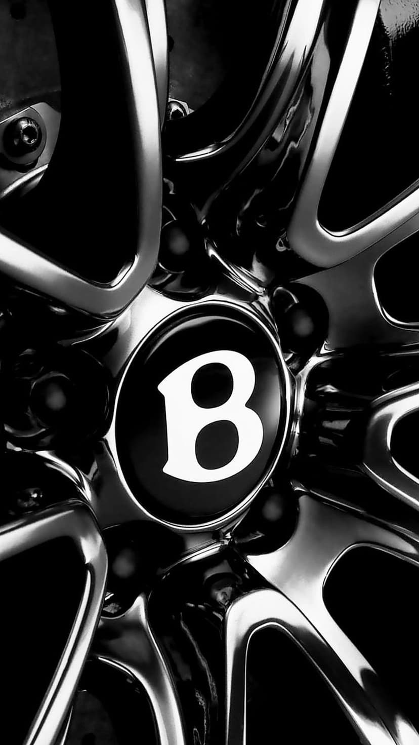 Bentley B logo centered on a metallic alloy wheel in high-contrast black and white automotive photography.