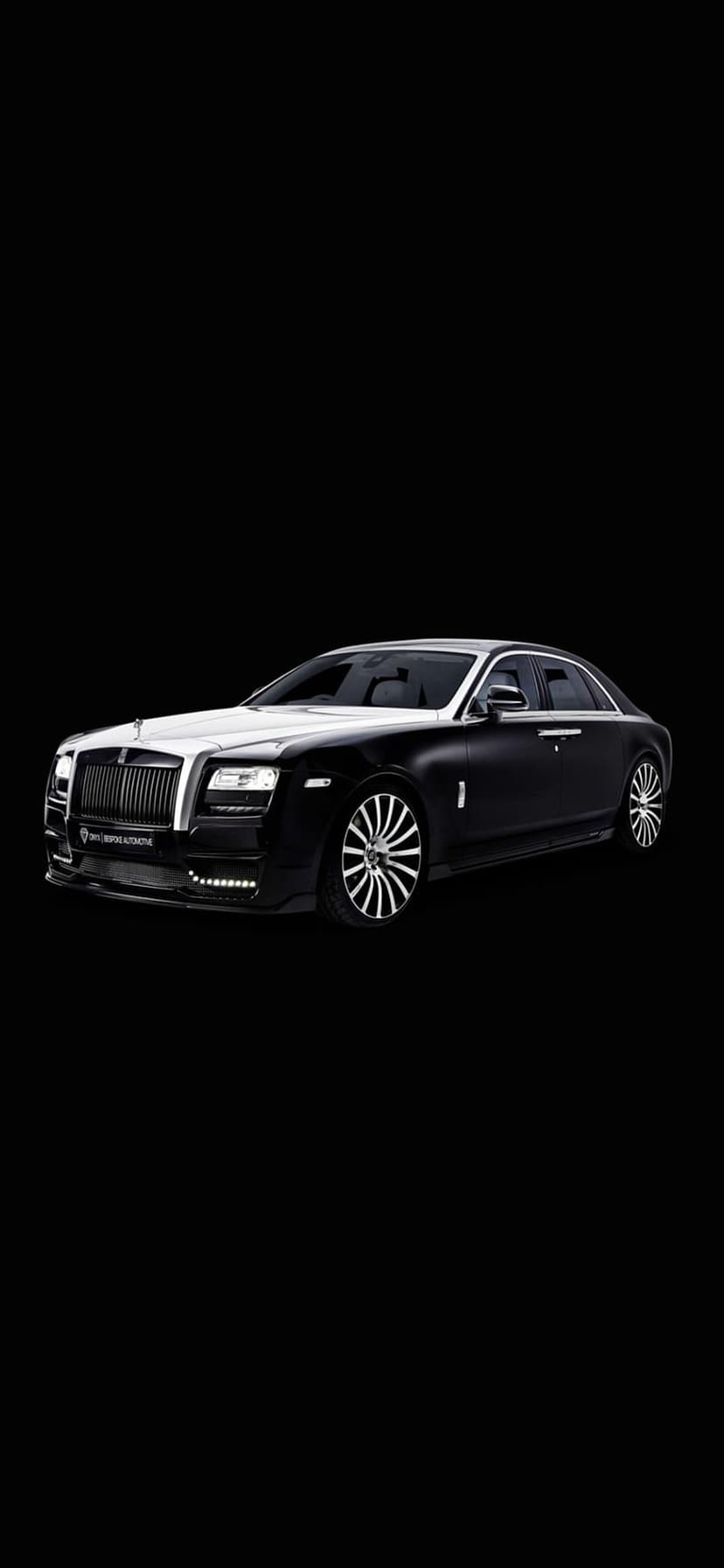 Rolls-Royce Ghost sedan with a silver grille and bonnet against a dark backdrop for mobile screens.