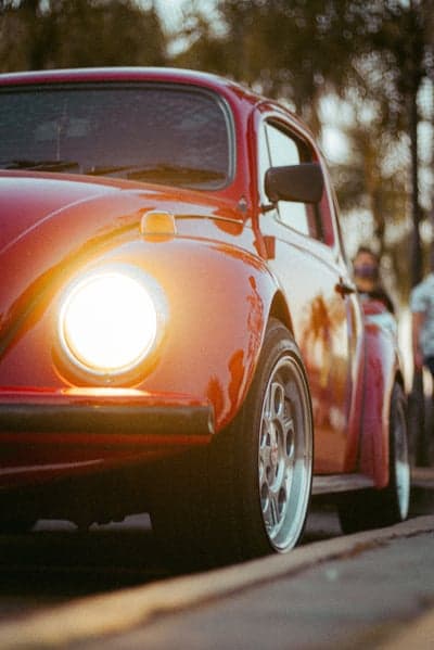 Red classic Volkswagen Beetle with glowing headlight