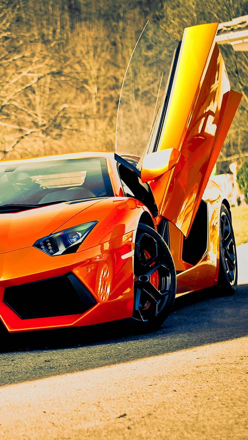 Orange Lamborghini Aventador with scissor doors open upwards against a soft green blurred outdoor background.