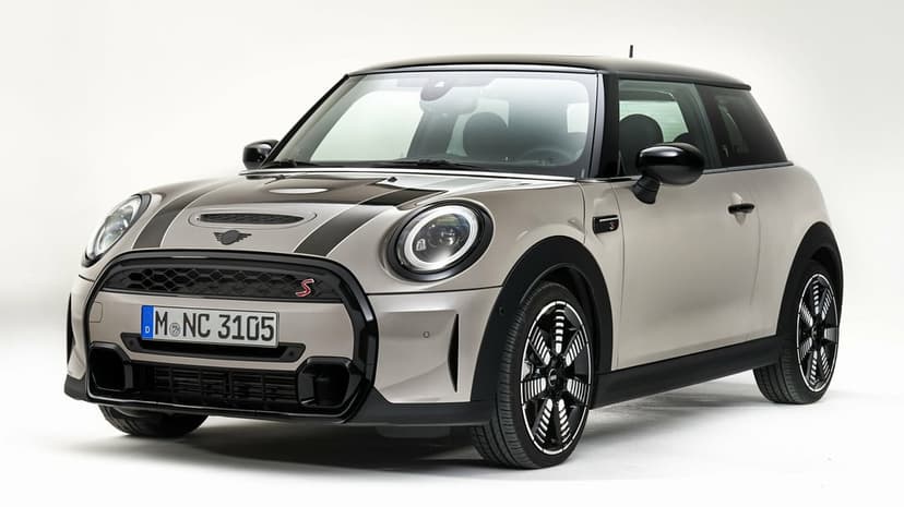 Silver Mini Cooper S hatchback with black racing stripes and LED headlights in a bright white studio.