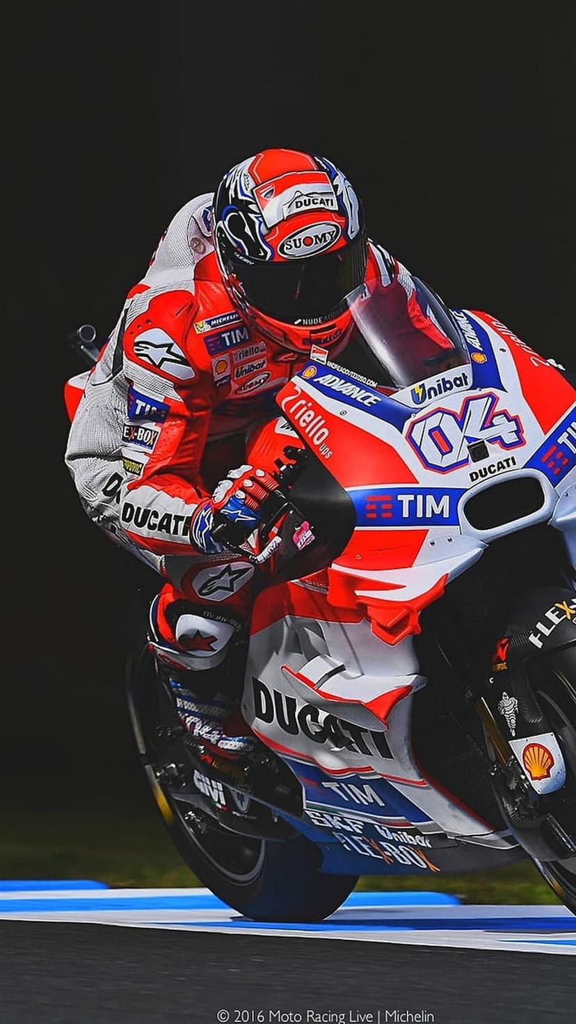 Ducati rider in red and white racing gear leans a motorcycle into a sharp track curve during a professional race.