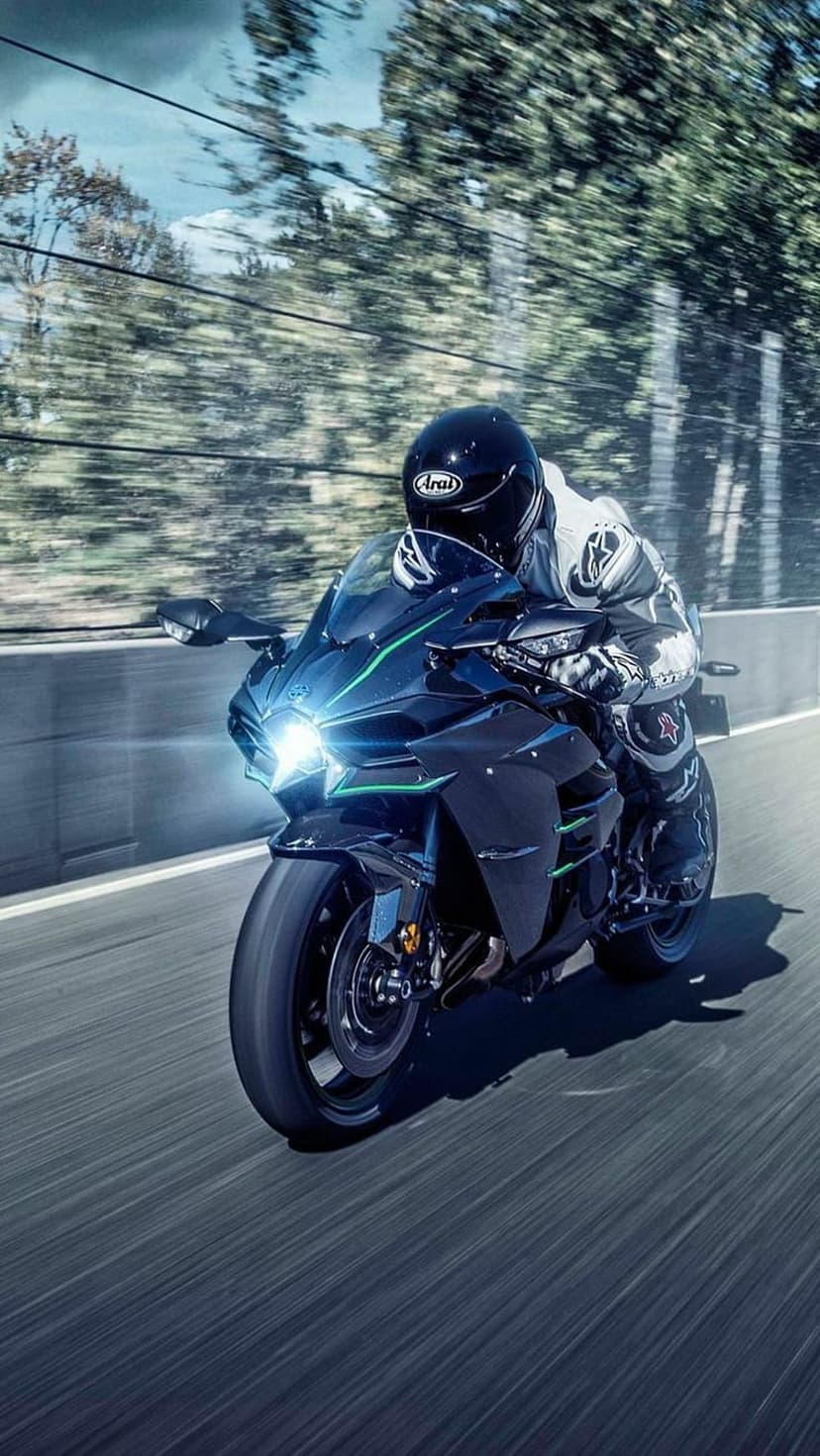 Kawasaki Ninja H2R motorcycle with glowing headlights leaning into a turn with heavy motion blur effects.