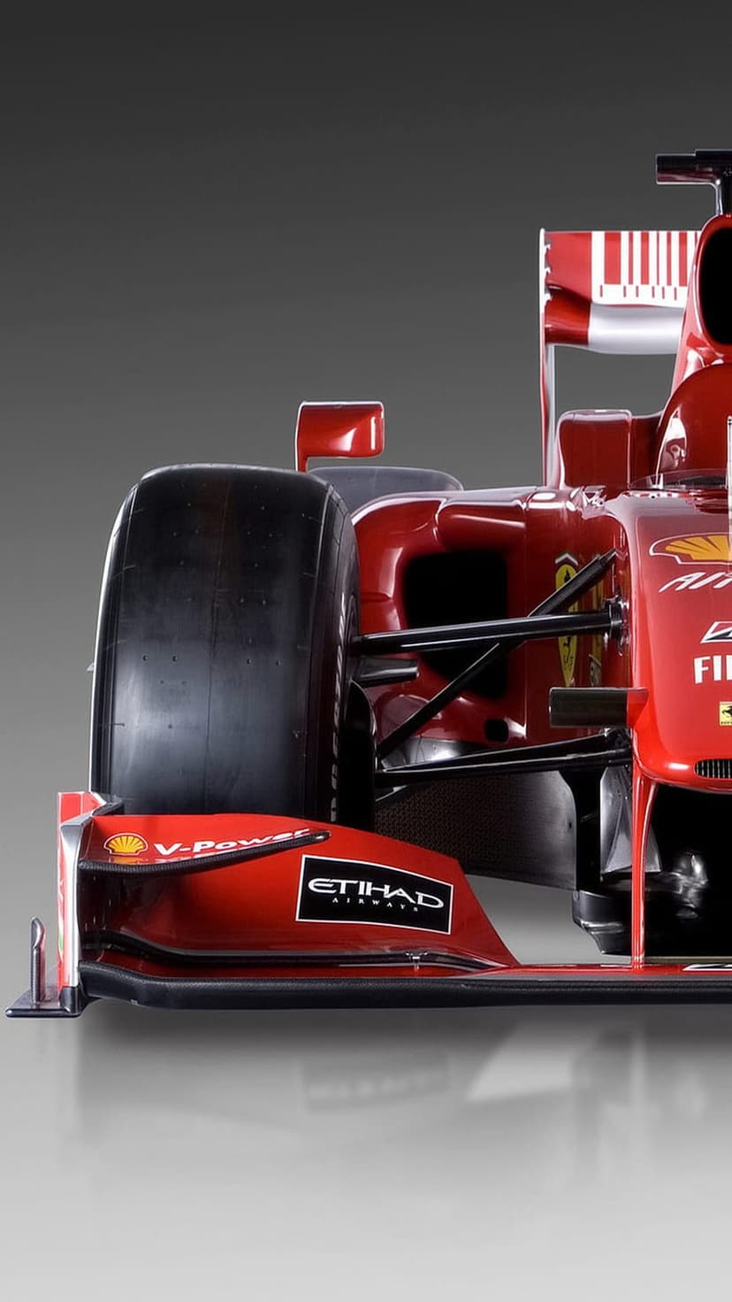 Ferrari Formula 1 car front wing and thick racing tire displayed against a neutral gray studio background.