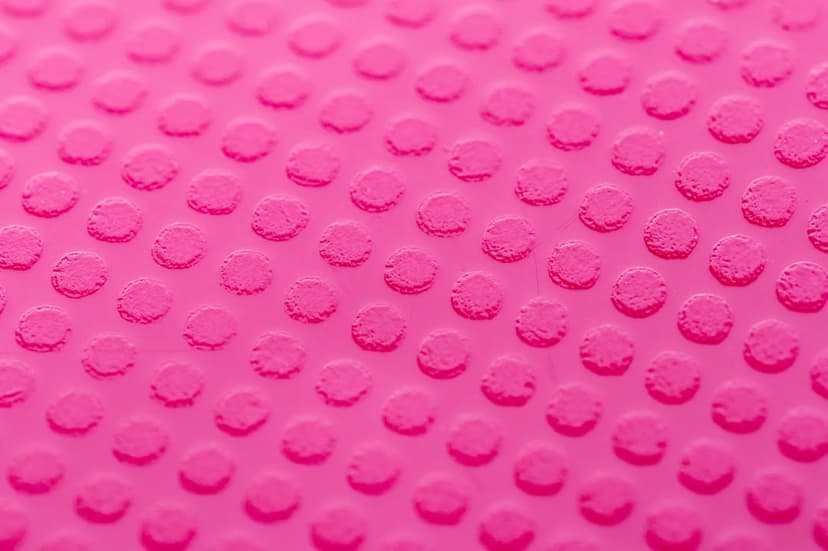 Elevated magenta polka dots arranged in a precise grid with soft shadows and 3D texture on a vibrant surface.