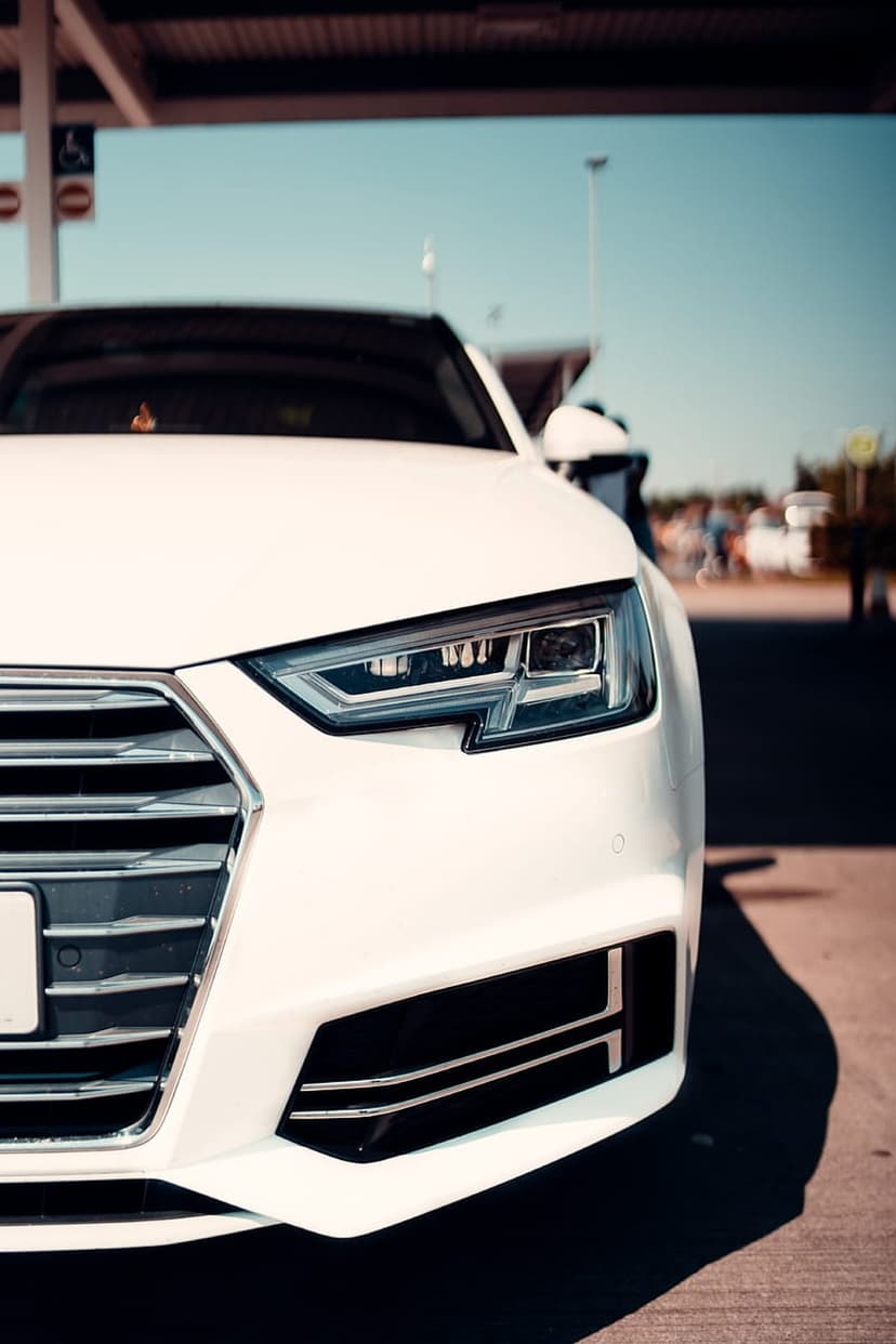 White Audi A4 LED headlight and hexagonal grille shown in a detailed close-up shot under bright natural sunlight.