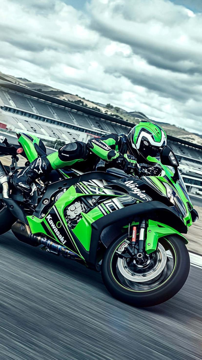 Kawasaki Ninja sportbike leaning into a racetrack curve with a rider in matching green and black gear.
