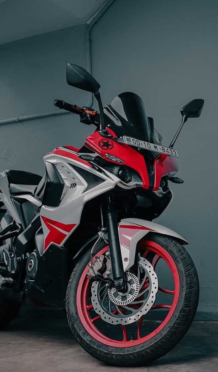 Red and white sportbike front view with a black windscreen and red rim parked against a gray studio wall.