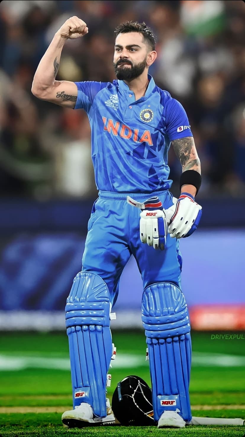 Virat Kohli celebrates victory in a blue India jersey and cricket helmet with a triumphant raised fist on field.