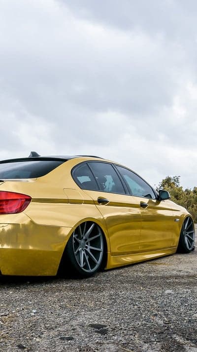 Gold BMW sedan with custom wheels and lowered stance