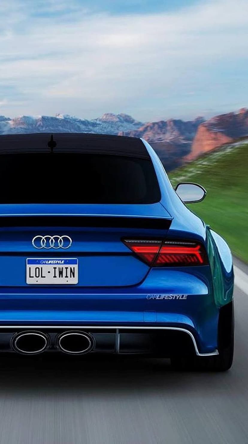 Blue Audi with custom plate driving on a winding mountain road during a vibrant golden hour sunset.