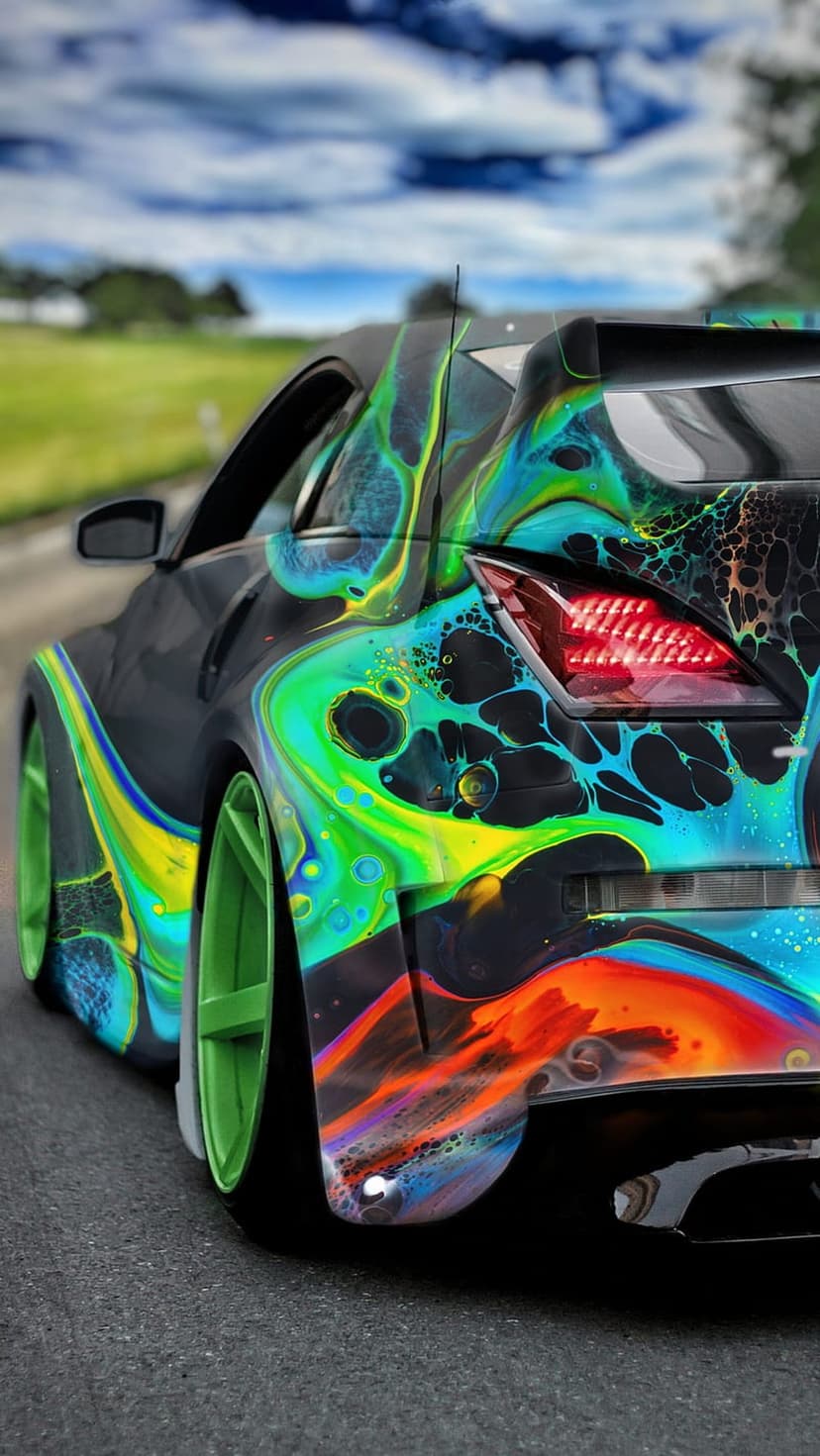 Sports car with neon green, blue, and orange swirling paint sits before a cloudy sky and green hills.