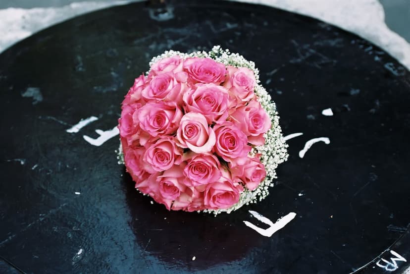 Pink rose bouquet with white baby's breath rests on a dark textured stone surface under soft lighting.
