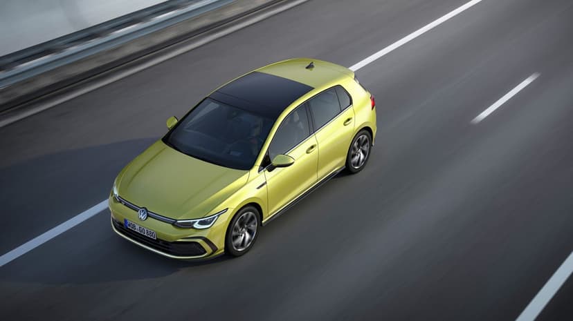 Lime green Volkswagen Golf hatchback driving on a grey highway with motion blur on wheels and road.