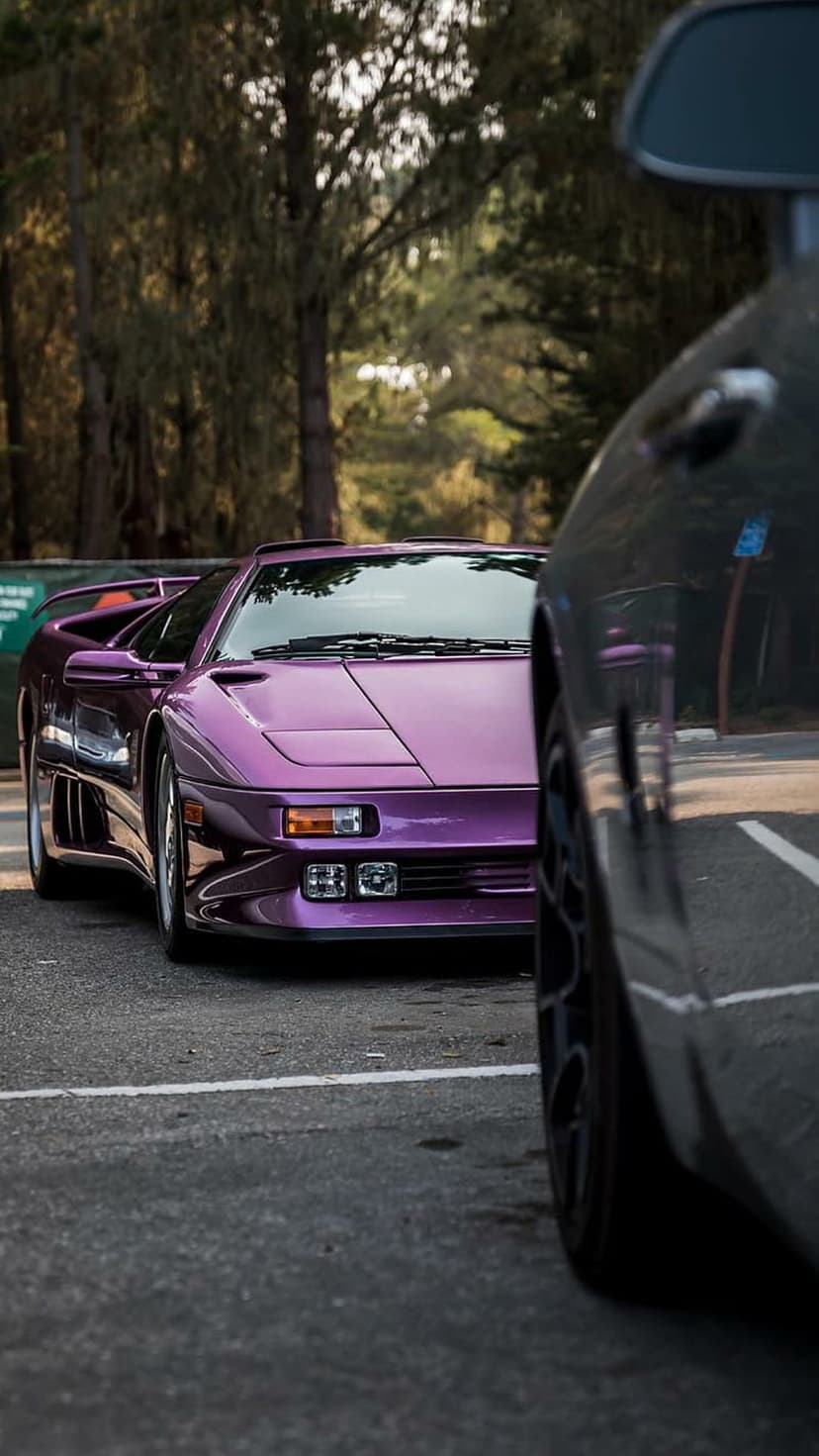 Purple Lamborghini Diablo supercar parked in an outdoor lot with trees in the background at a low angle view.