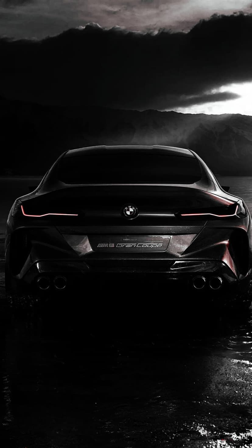 Black BMW M8 Gran Coupe rear view with glowing red taillights partially submerged in dark reflective water.