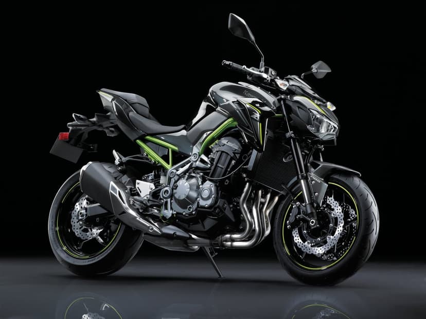 Black Kawasaki Z900 motorcycle with a lime green frame and wheels on a reflective dark studio floor.