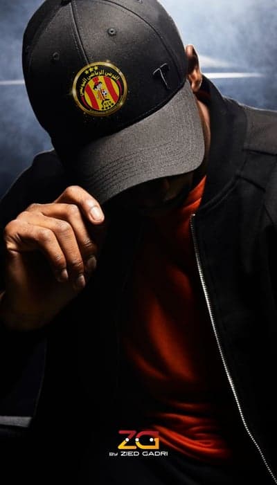 Man in Black Cap and Jacket, Red T-Shirt, Club Logo