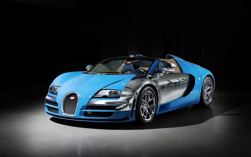 Bugatti Veyron Grand Sport Vitesse with blue paint and polished chrome bodywork in a dark studio.