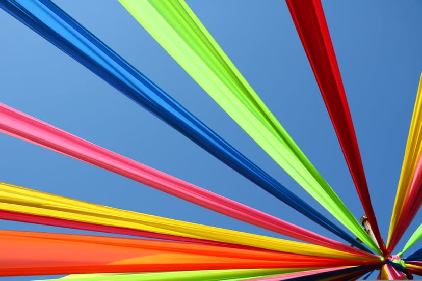 Multi-colored fabric streamers radiate from a central point against a vivid, cloudless blue sky background.