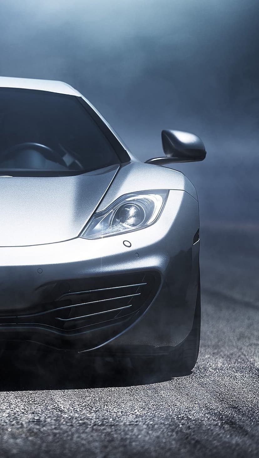 Silver sports car front profile with glowing headlights and side mirrors visible through thick grey smoke.