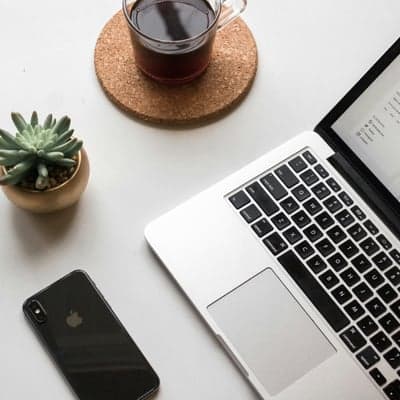 Laptop, coffee, succulent, and iPhone on a white desk