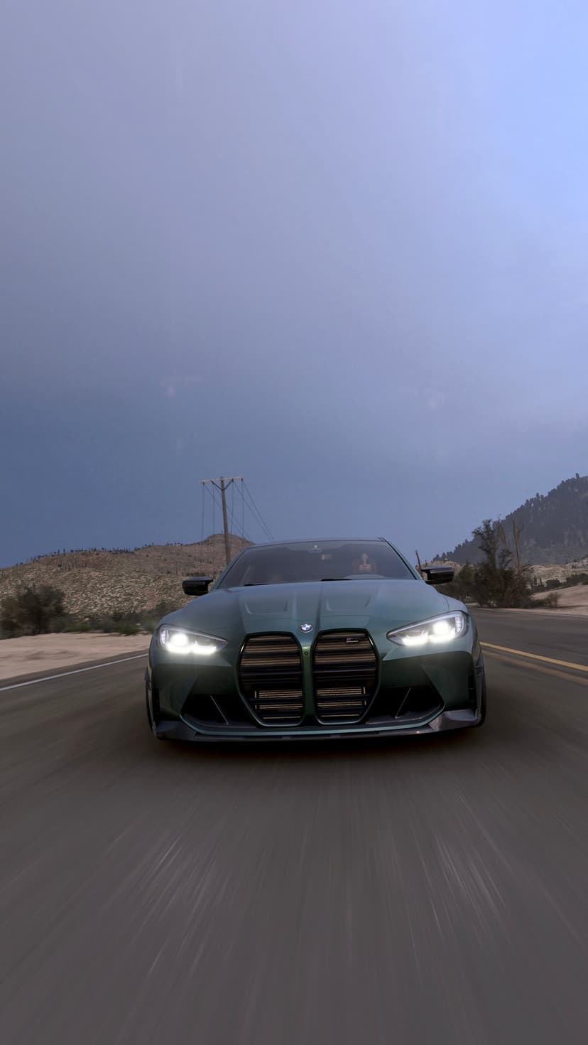 Green BMW M4 sports car with glowing headlights speeding on a desert road under a dramatic dusk sky.