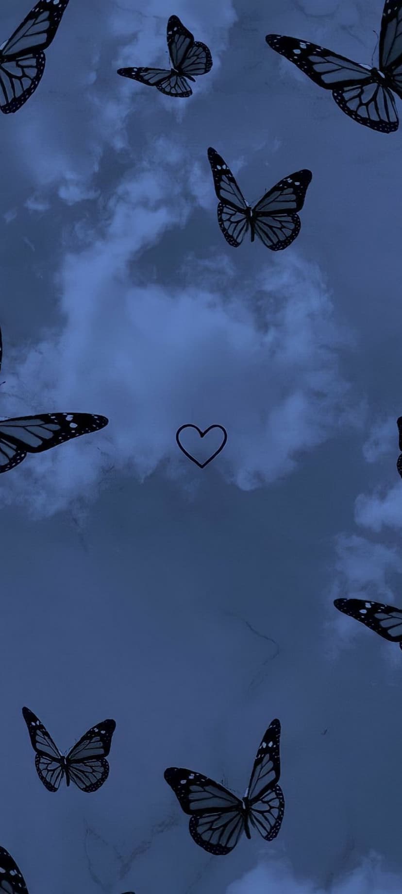 Monarch butterflies surround a black heart outline amidst deep blue storm clouds in a vertical night sky view.