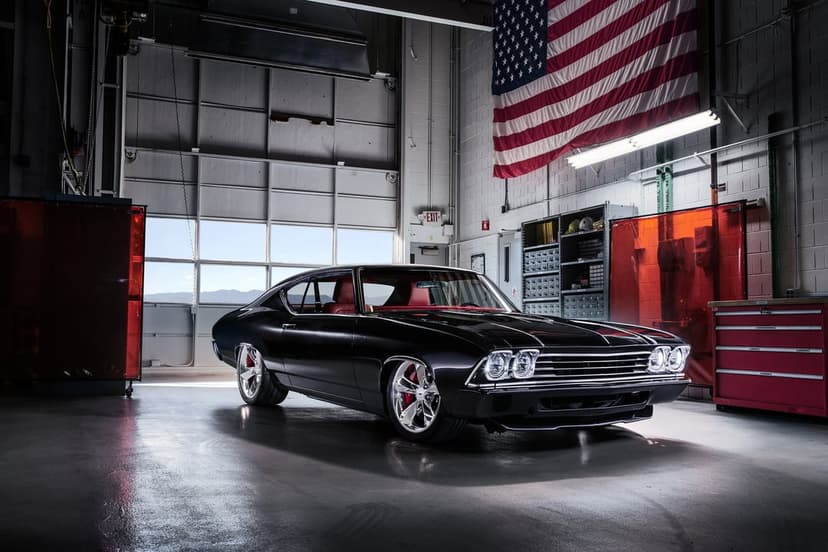 Black 1968 Chevy Chevelle with red interior and chrome wheels in a garage with an American flag background.
