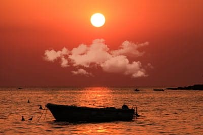 Fiery Sunset Over Serene Ocean Boat Mobile Background